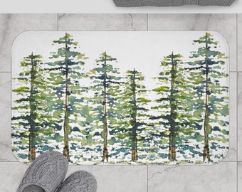 May include: White bath mat with a watercolor design of green trees. The trees are arranged in a row across the mat.