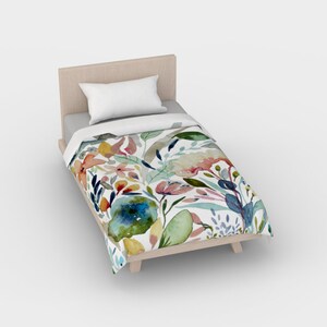 May include: A white twin-sized bed with a floral duvet cover. The duvet cover features a watercolor design of colorful flowers and leaves on a white background.