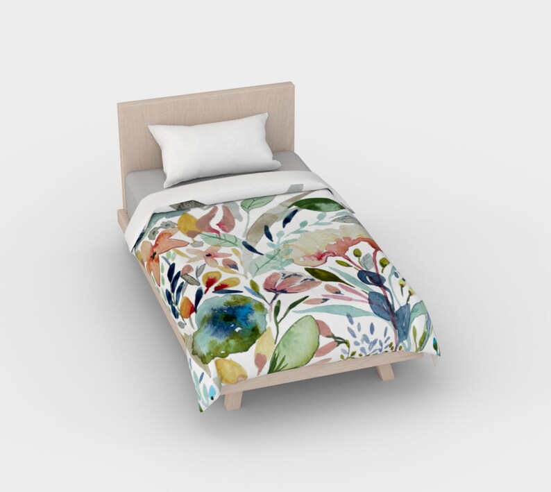 May include: A white twin-sized bed with a floral duvet cover. The duvet cover features a watercolor design of colorful flowers and leaves on a white background.