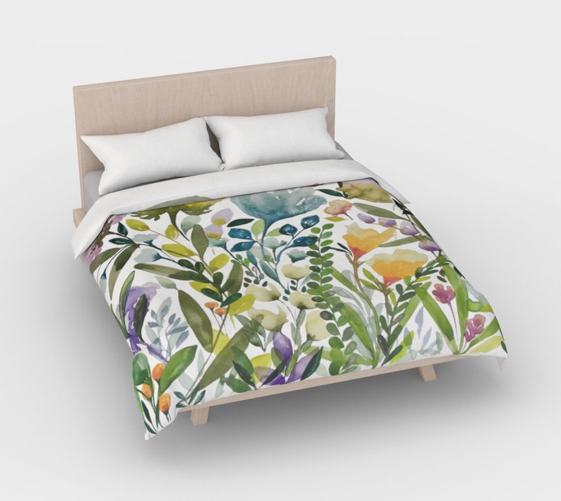 K&ouml;nnte beinhalten: Ein wei&szlig;er Bettbezug mit einem Blumenmuster aus gr&uuml;nen Bl&auml;ttern, gelben, orangefarbenen, blauen und violetten Blumen.