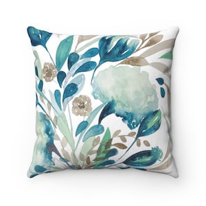 May include: A square throw pillow with a watercolor floral design featuring blue, green, and brown flowers and leaves on a white background.