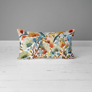 May include: A rectangular throw pillow with a watercolor floral pattern. The pillow features a variety of flowers in shades of orange, yellow, blue, and green on a white background.