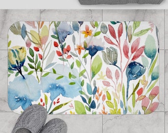 Puede incluir: Una alfombra de baño de acuarela con un diseño floral que presenta flores azules, rosas, amarillas, verdes y rojas sobre un fondo blanco.