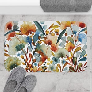 May include: A watercolor floral bath mat with a white background and a colorful design of flowers and leaves in shades of blue, green, orange, and red.