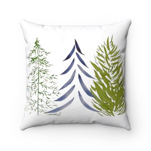 May include: White square throw pillow featuring a watercolor design of three stylized evergreen trees. The trees are in shades of green and blue, set against a white background. A decorative accent for a living room or bedroom.