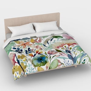 May include: A white duvet cover with a watercolor floral pattern featuring pink, yellow, blue, and green flowers and leaves.