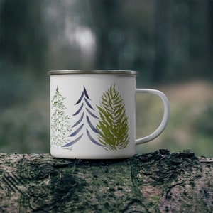 May include: White enamel camping mug with a blue, green, and white tree design.