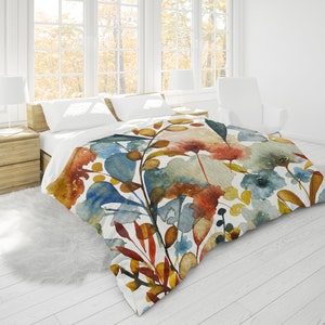 May include: A white duvet cover with a watercolour floral pattern featuring blue, orange, yellow, and red flowers and leaves.