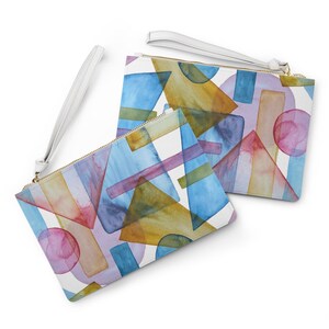 May include: Two white zippered pouches with a geometric pattern of watercolor shapes in shades of blue, pink, yellow, and green. The pouches have white straps.