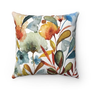 May include: A watercolor floral pillow cover with a white background and a colorful floral pattern. The flowers are in shades of orange, yellow, blue, and green.
