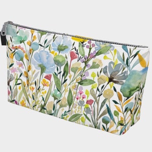 May include: A white zippered pouch with a floral pattern. The pattern features watercolor-style flowers in shades of blue, yellow, green, pink, and red.