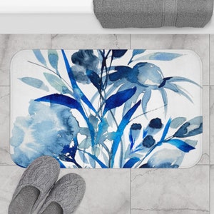 May include: A blue and white watercolor floral bath mat with a modern abstract design. The mat features a variety of blue flowers and leaves on a white background.