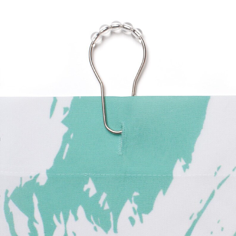 May include: A silver shower curtain ring with clear plastic beads. The ring is attached to a green and white shower curtain.
