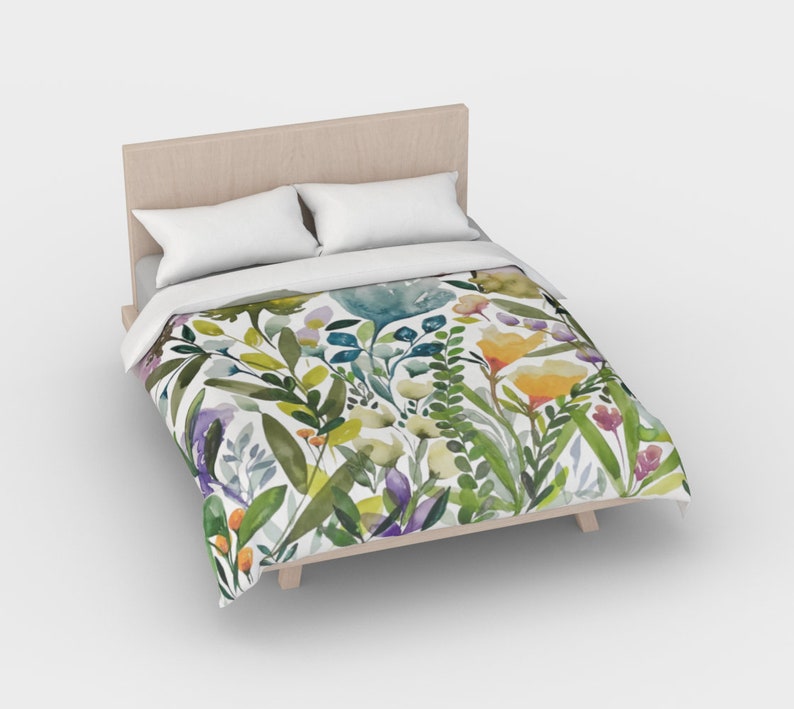 K&ouml;nnte beinhalten: Ein wei&szlig;er Bettbezug mit einem Blumenmuster aus gr&uuml;nen Bl&auml;ttern, gelben, orangefarbenen und violetten Bl&uuml;ten.