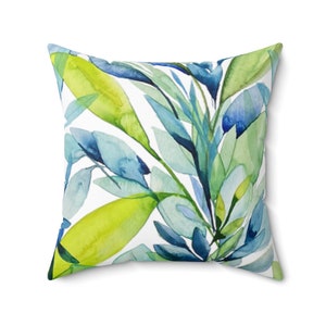 May include: A square throw pillow with a white background and a watercolor design of blue and green leaves.