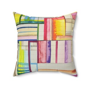 May include: A square throw pillow with a geometric pattern in shades of pink, yellow, blue, green, and purple. The pattern is made up of overlapping rectangles and squares.