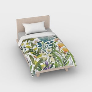 K&ouml;nnte beinhalten: Ein wei&szlig;er Bettbezug in Twin-Gr&ouml;&szlig;e mit einem Aquarell-Blumenmuster mit gr&uuml;nen Bl&auml;ttern, gelben, orangefarbenen und violetten Bl&uuml;ten.