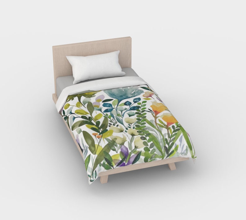 K&ouml;nnte beinhalten: Ein wei&szlig;er Bettbezug in Twin-Gr&ouml;&szlig;e mit einem Aquarell-Blumenmuster mit gr&uuml;nen Bl&auml;ttern, gelben, orangefarbenen und violetten Bl&uuml;ten.