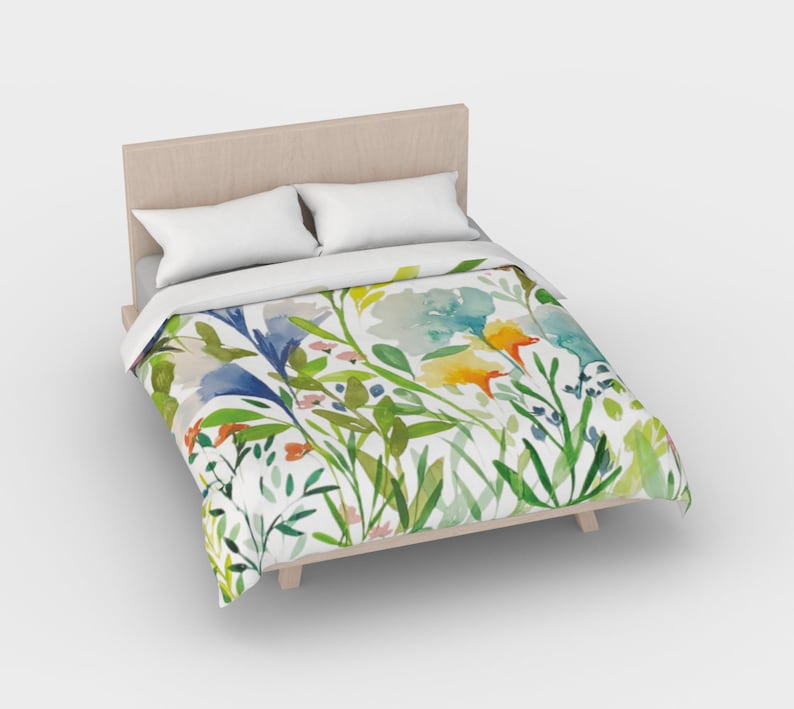 May include: A white duvet cover with a watercolor floral print featuring blue, yellow, green, and orange flowers. The duvet cover is on a bed with a wooden headboard.
