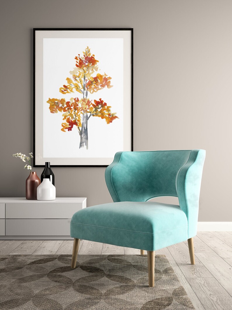 Op de afbeelding: Een tealblauwe fauteuil met een uniek uitgesneden ontwerp in de rug staat op een tapijt met patroon voor een witte muur met een ingelijst aquarel schilderij van een boom met oranje en gele bladeren.