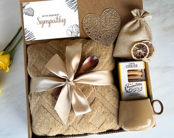 May include: A gift box filled with sympathy gifts, including a brown throw blanket, a wooden spoon, a bag of lemon cookies, a small bag of dried lemon slices, and a card that reads "With Deepest Sympathy".