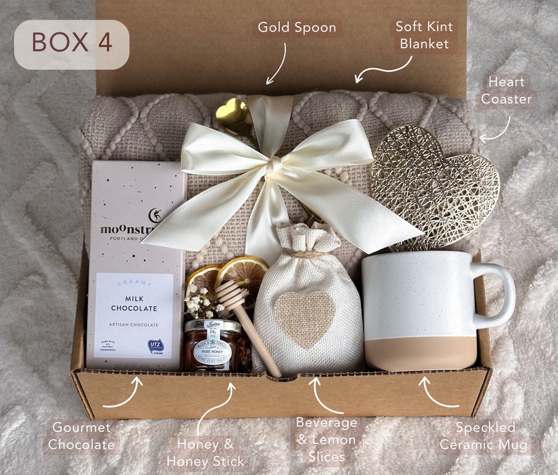Peut inclure: Une bo&icirc;te cadeau &eacute;tiquet&eacute;e "BOX 4" remplie d'une vari&eacute;t&eacute; d'articles, dont une couverture en tricot doux, un sous-verre en forme de c&oelig;ur, une tasse, un sac de miel, un pot de miel, un b&acirc;ton de miel, une barre de chocolat et des tranches de citron.