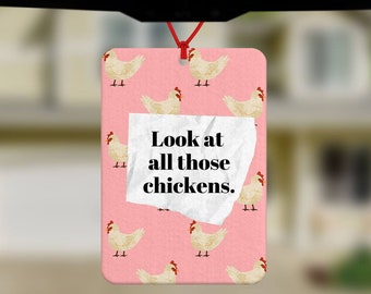 May include: A pink car air freshener with a white paper note that says "Look at all those chickens." The air freshener has a pattern of white chickens on a pink background.