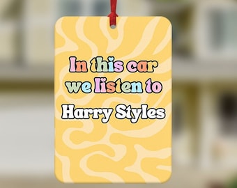 May include: Yellow car air freshener with the text "In this car we listen to Harry Styles" in rainbow colors.