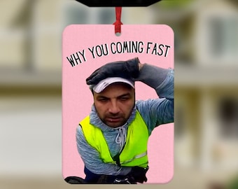 May include: A pink car air freshener with a photo of a man wearing a yellow safety vest and the text "WHY YOU COMING FAST".