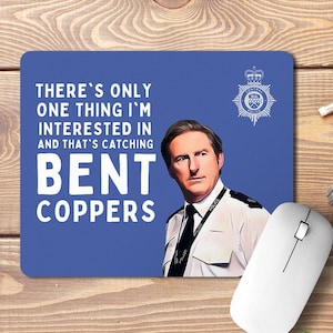 May include: A blue mouse mat with a white border featuring a cartoon image of a man in a police uniform. The text on the mouse mat reads "There's only one thing I'm interested in and that's catching bent coppers."