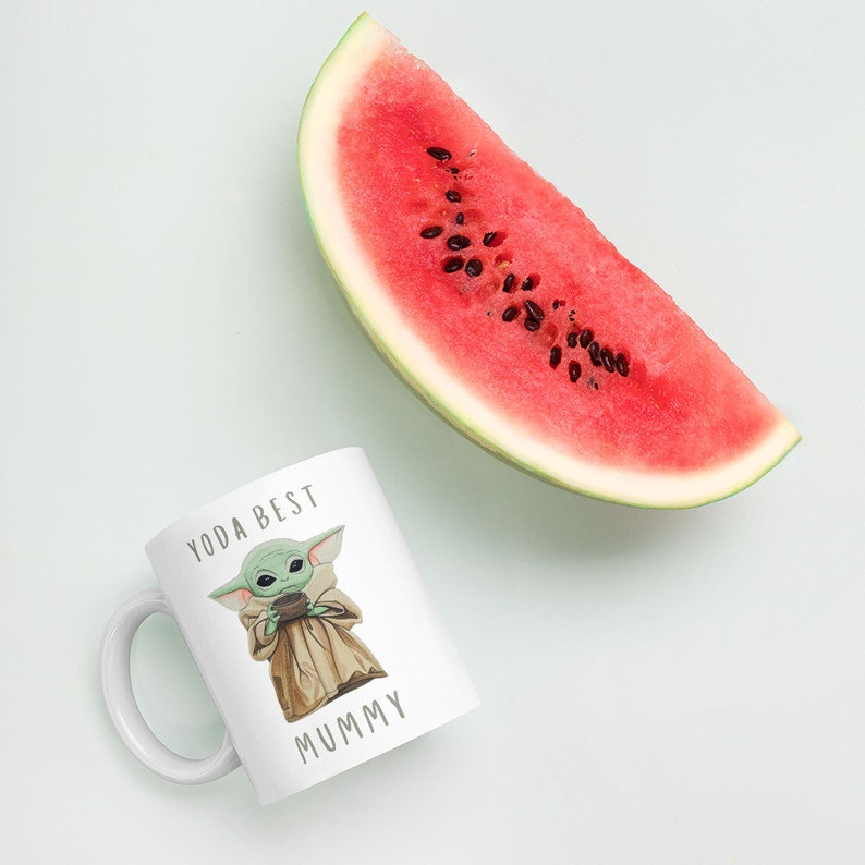 May include: White ceramic mug with a green cartoon character holding a cup and the text "Yoda Best Mummy".