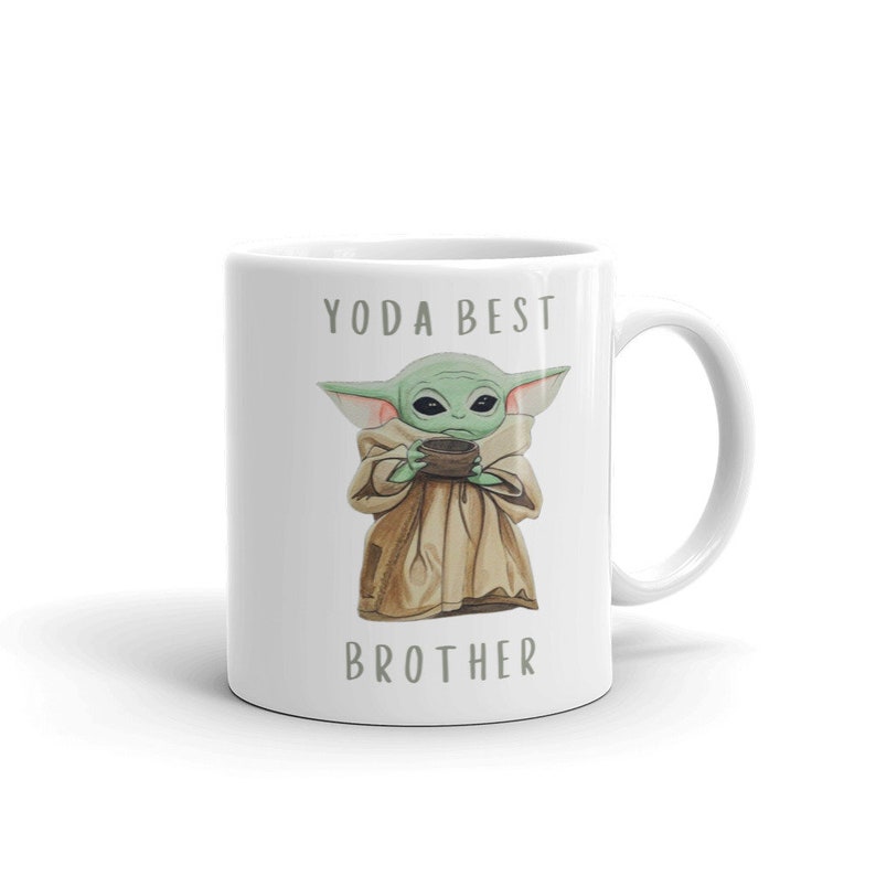 May include: White ceramic mug with a green alien character holding a cup. The text "YODA BEST BROTHER" is printed on the mug.