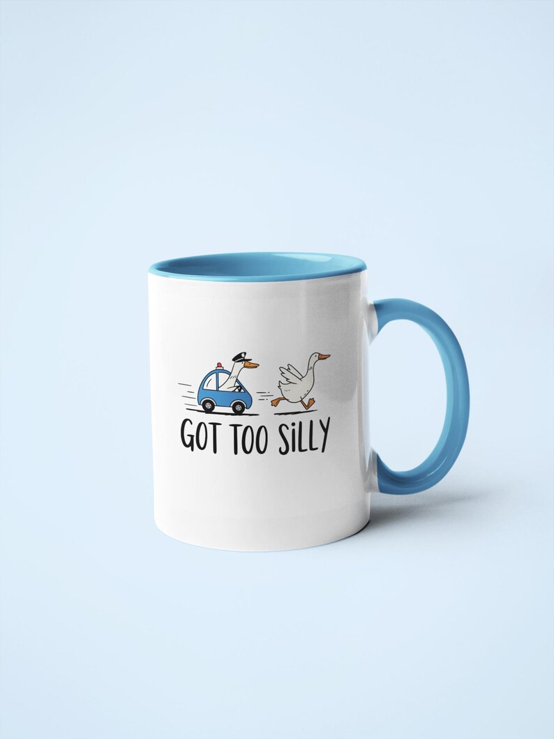 May include: White ceramic mug with a blue interior and handle. The mug features a cartoon illustration of a goose being chased by a police car, with the text "GOT TOO SILLY".