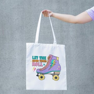 May include: White tote bag with a purple roller skate design and the text "LET THE GOOD TIMES ROLL". The roller skate has yellow wheels. The bag is held up by a person.