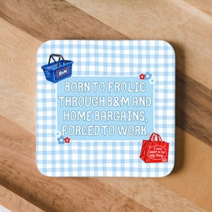 May include: A square coaster with a light blue and white gingham pattern. It features a blue shopping basket, a red shopping bag, and the text: BORN TO FROLIC THROUGH B&M AND HOME BARGAINS, FORCED TO WORK. Small red and blue flower icons are included.