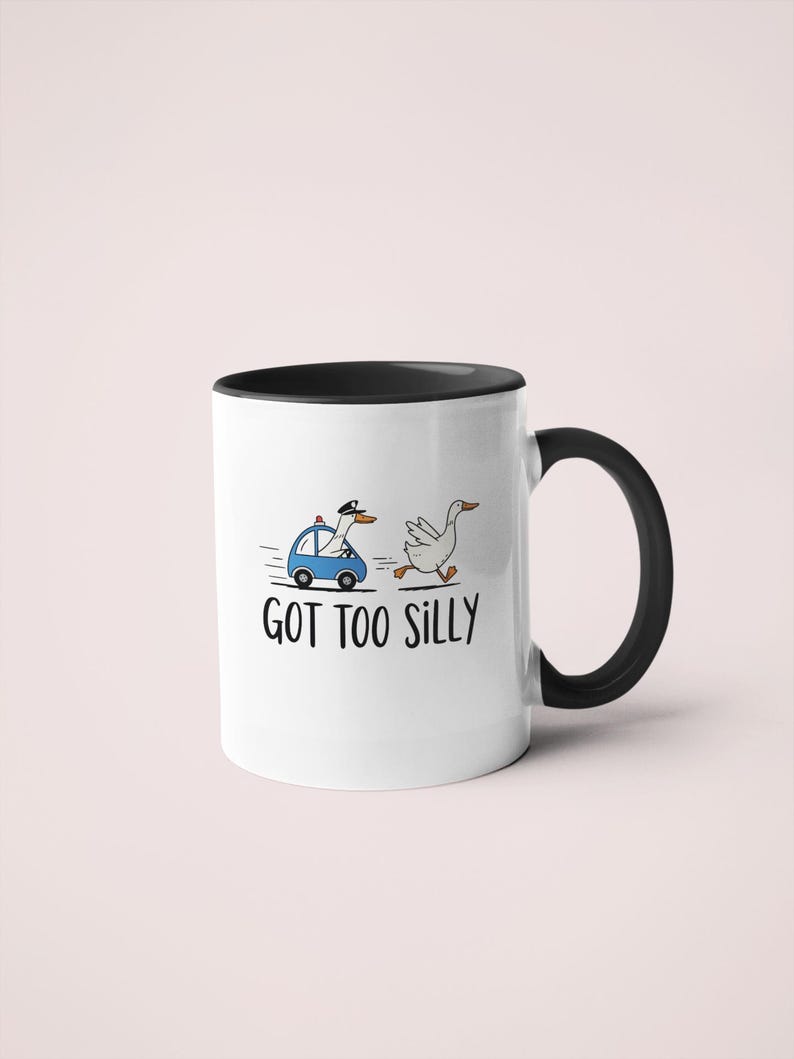May include: White ceramic mug with a black interior and handle. The mug features a cartoon illustration of a goose being chased by a police car, with the text "GOT TOO SILLY" below the illustration.