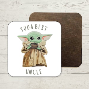 Pode incluir: Um coaster quadrado branco com um personagem de desenho animado verde segurando uma tigela. O texto "Yoda Best Uncle" está impresso no coaster.