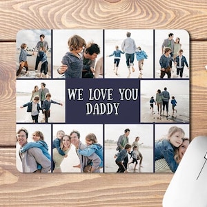May include: A rectangular mouse pad featuring a photo collage of family beach scenes and the centred text WE LOVE YOU DADDY in white capital letters against a dark blue background. The images show various outdoor activities on the sand.