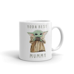 May include: White ceramic mug with a green alien character holding a cup. The text "YODA BEST MUMMY" is printed on the mug.