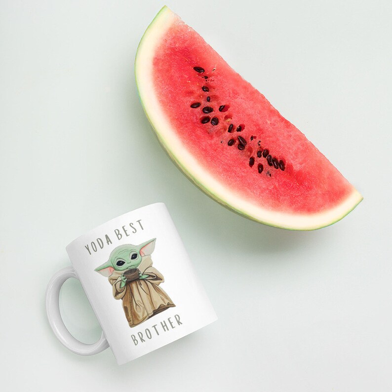 May include: White ceramic mug with a green cartoon character holding a cup and the text "Yoda Best Brother".