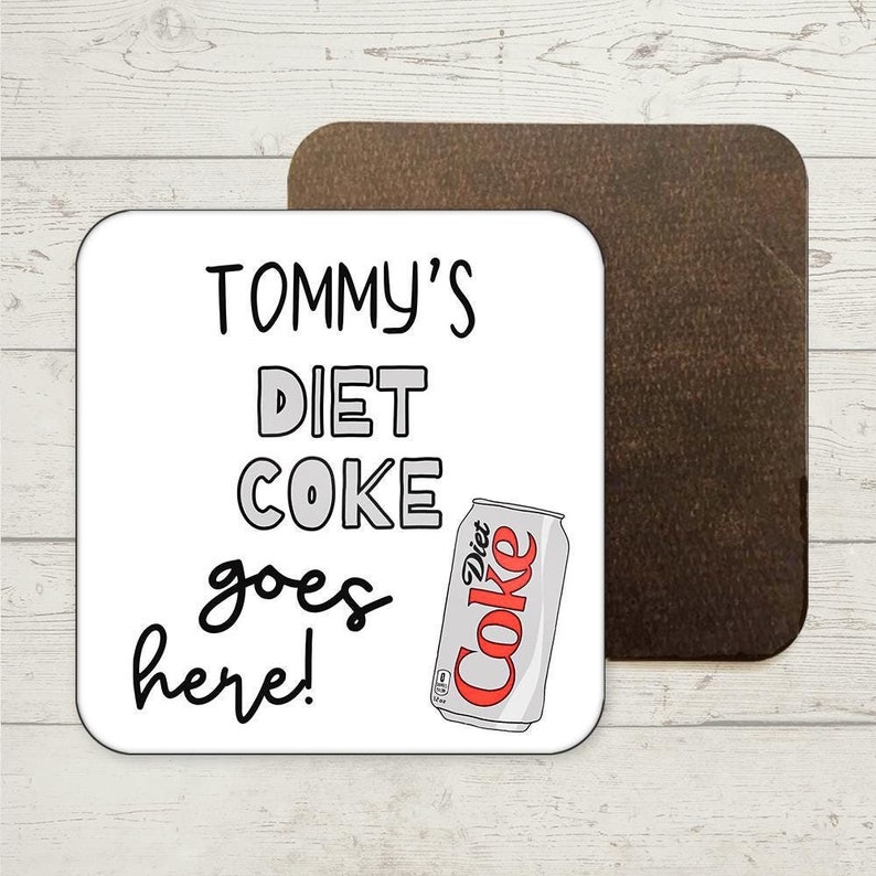 Peut inclure: Sous-verre blanc avec du texte noir qui dit "TOMMY'S DIET COKE goes here!" et une image de dessin anim&eacute; d'une canette de Coca-Cola light.