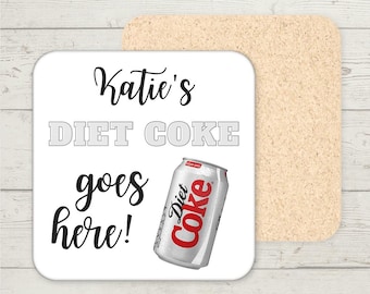 May include: White coaster with black text that reads "Katie's Diet Coke goes here!" and a silver can of Diet Coke.