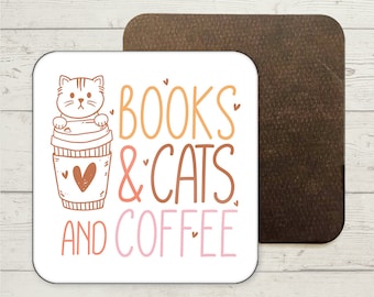 May include: White square coaster with a cartoon cat in a coffee cup. The text "BOOKS & CATS AND COFFEE" is written in orange, pink, and brown.