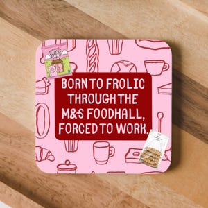 May include: A square coaster with a light pink background featuring a pattern of food outlines. A dark red rectangle in the centre displays the text: BORN TO FROLIC THROUGH THE M&S FOODHALL, FORCED TO WORK. Includes a Percy Pig candy and cookie graphic.