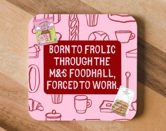 May include: A square coaster with a light pink background featuring a pattern of food outlines. A dark red rectangle in the center displays the text: BORN TO FROLIC THROUGH THE M&S FOODHALL, FORCED TO WORK. Includes a Percy Pig candy and cookie graphic.