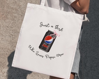 May include: White tote bag featuring a Pepsi Max can design with a pink bow. The text reads "Just a Girl Who Loves Pepsi Max" in black script. The bag has two handles.