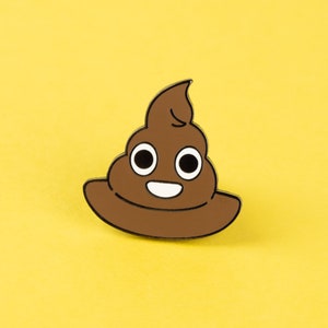 May include: A brown enamel pin in the shape of a smiling poop emoji with a black outline. The pin has white eyes and a white smile. The background is a solid yellow.
