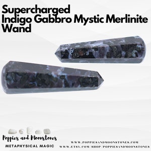 May include: Two indigo gabbro mystic merlinite wands, one lying horizontally and the other vertically, both with a dark blue and white marbled pattern. Supercharged Indigo Gabbro Mystic Merlinite Wand. Poppies and Moonstones Metaphysical Magic. www.poppiesandmoonstones.com www.etsy.com/shop/poppiesandmoonstones