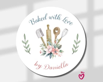 May include: A round white sticker featuring the text Baked with Love in blue and by Daniella in pink. The design includes a watercolor illustration of a spatula, rolling pin, wooden spoon, and wire whisk nestled in a bouquet of pink flowers.