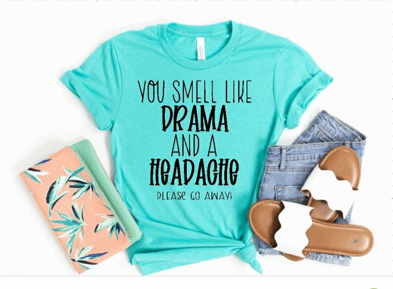 May include: A turquoise t-shirt with the text "You smell like drama and a headache. Please go away!" printed in black.